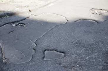 Broken asphalt and cracks on the road surface