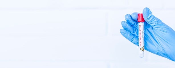 Hand holds a test tube containing a blood sample, test tube with blood for Covid-19 (coronavirus)...