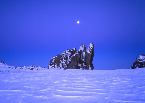 The moon above a rocky outcrop in a frozen land