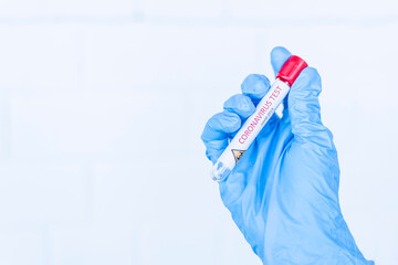 Hand holds a test tube containing a blood sample, test tube with blood for Covid-19 (coronavirus) analyzing