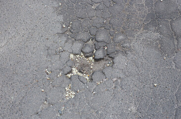 Broken asphalt and cracks on the road surface