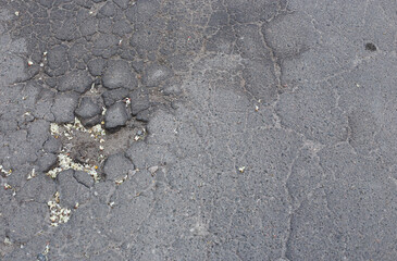 Broken asphalt and cracks on the road surface