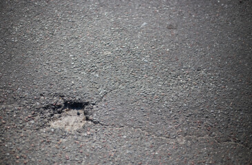 Broken asphalt and cracks on the road surface