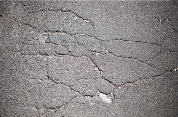 Broken asphalt and cracks on the road surface