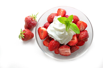 Dessert from fresh strawberries, whipped cream and peppermint garnish in a glass bowl, isolated...