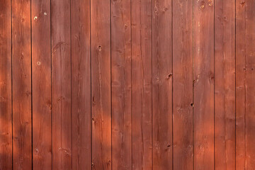 Brown wooden vertical plank fence with sun glare.
