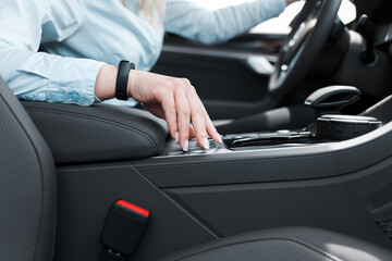 Woman holds her hand on the wheel of the car settings. Ьodern car features concept