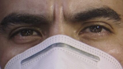 Close-up of man's face with a face mask, brown eyes, serious look