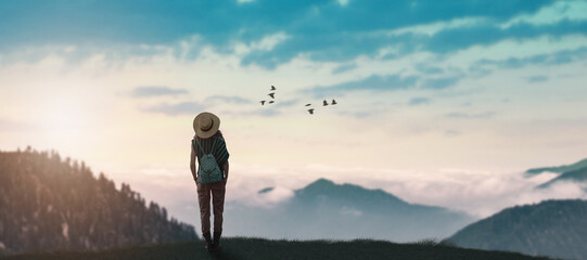 traveler girl in hat with backpack exploring misty sunny mountains.