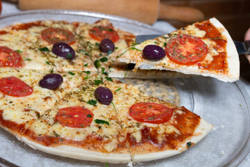 Margarita pizza from Brazilian cuisine, cheese with tomato sauce, melted cheese, blurred background of rolling pin