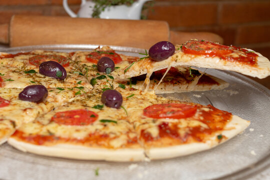 Margarita pizza from Brazilian cuisine, cheese with tomato sauce, melted cheese, blurred background of rolling pin