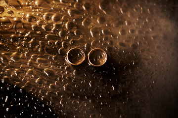 Wedding rings with smoke and water droplets. Wedding gold rings bride and groom.