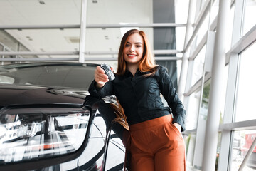 Happy pretty young woman with a key in hands near her new car