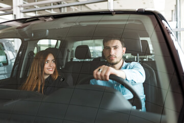 Young family couple in their new car at the auto dealership
