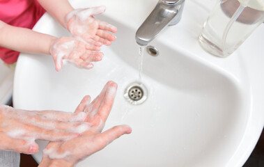 Children wash their hands with soap in the sink. Children and personal hygiene during the COVID-19 pandemic