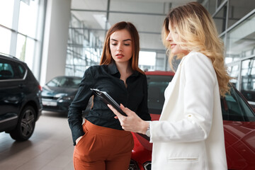 Car dealership manager shows documents for a deal to a client