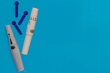 Diabetes. Monitoring blood glucose in diabetics. Glucose meter. Disposable needles. Test strips for glucometer. A healthy lifestyle diabetic. Macro photo. Blue background