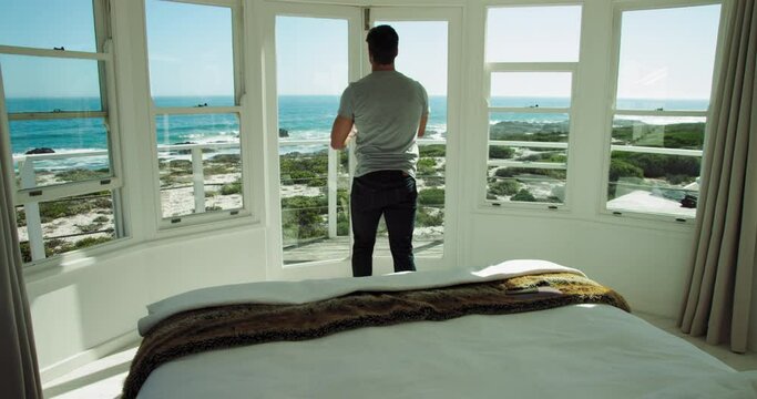 WS Man walking out on balcony and looking at view with beach and sea / Claremont, Cape Town, South Africa