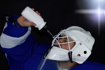 Hockey goalie drinks water.Detail of a male face in a white goalie hockey mask.This is a detail...