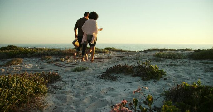 WS Couple walking on beach with drinks / Claremont, Cape Town, South Africa