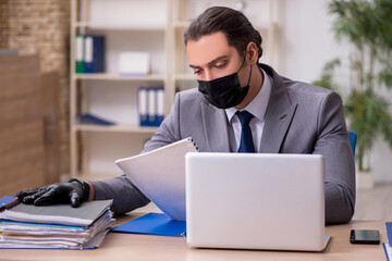 Young male employee in the office during pandemic disease