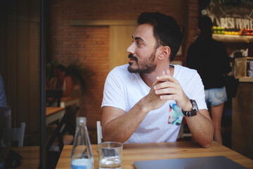 Young handsome man entrepreneur posing while sitting with open laptop computer