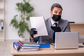 Young male employee in the office during pandemic disease