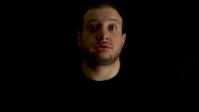 Portrait of young, bored man on black background. Tired and outworn concept.