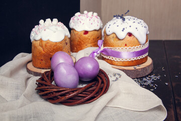 Painted Easter eggs in a wicker nest and Easter cakes, decorated with lavender and marshmallows