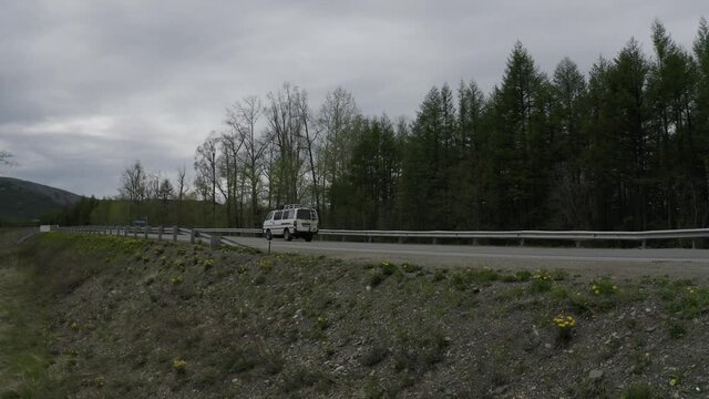 On the Kolyma highway car rides. You can see the trees. Evening time.