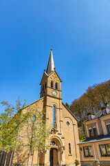 Fototapeta premium Facade of Saint Donatus Church and tower with the cross in Larochette, Luxembourg