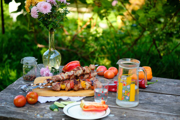 Freshly cooked barbecue and vegetables on a wooden table. Summer lunch in nature. Tasty meat dish...