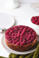 Morning breakfast with raspberry cheesecake. Dessert and raspberries in a plate on a white wooden table.