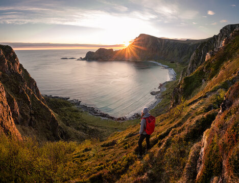 A woman hiking during midnight sun. Active vacation in Norway. Located on Andøya island in Vesterålen north of Norway. Sunset and backpack girl.