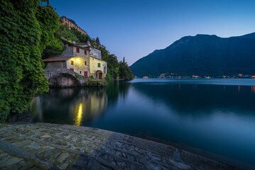 Scenic picture of Nesso on the Como lake in Italy with stone foreground at the blue hour