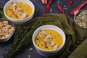 Pumpkin cream soup with breadcrumbs, hot pepper and thyme, garnished with pumpkin seeds.