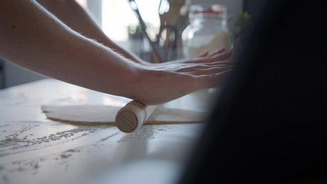 side view, Anonymous person using a rolling pin to Roll out Dough at Home. Making Pasta.