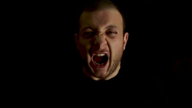 Serious young male is screaming portrait on black background. Sad face of psycho, crazy angry man, Horror and mysterious concept. Dangerous man.