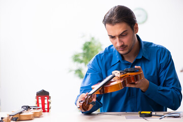 Young male repairman repairing violin
