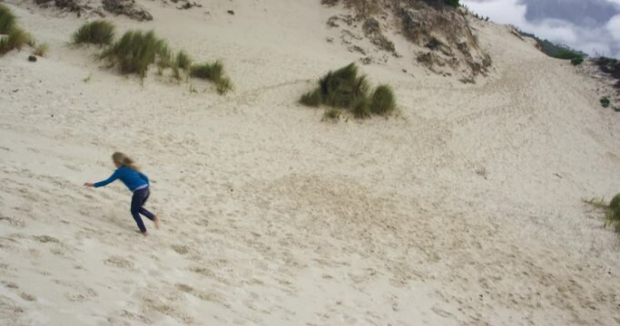 WS TS Girl (8-9) making sand angel and running down on sand dune / Cape Town, South Africa