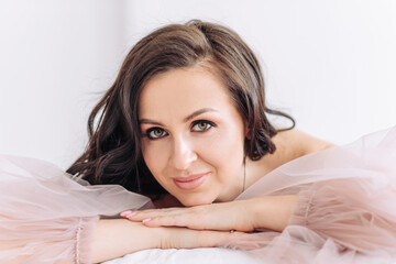 Fototapeta premium Cheerful and happy bride in a beautiful pink light wedding dress. Gorgeous makeup and hairstyle