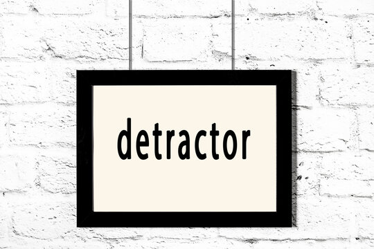 Black frame hanging on white brick wall with inscription detractor