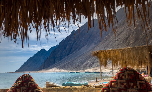 Summer beach with cliffs around a cozy bay on the Red Sea coastline at Dahab resort in Egypt.