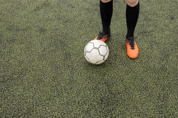 soccer ball with his feet on the football field.