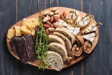 Delicious snacks. Several varieties of cheese, nuts, ciabatta and sausage on an old wooden table. Food for a romantic dinner.Top view.