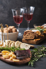 Delicious snacks and wine. Several varieties of cheese, nuts, ciabatta and sausage on an old wooden table. Food for a romantic dinner.