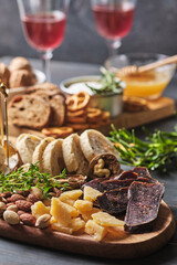 Delicious snacks and wine. Several varieties of cheese, nuts, ciabatta and sausage on an old wooden table. Food for a romantic dinner.