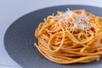 Spaghetti with tomato sauce and parmesan. Pasta on a white wooden table. Italian dish for lunch.