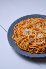 Spaghetti with tomato sauce and parmesan. Pasta on a white wooden table. Italian dish for lunch.