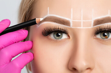 Woman Having Permanent Make-up Tattoo on her Eyebrows. Closeup beautician doing tattooing eyebrow....